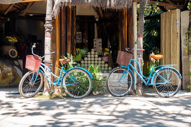 Tulum, Mexico. May 25, 2021. Two bicycles parked on side of road in front of a store with stack of jars