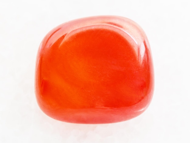 Tumbled carnelian gem on white marble