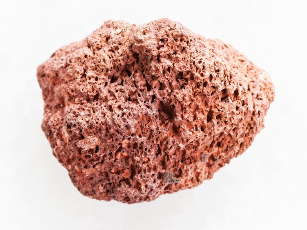 Tumbled red pumice pebble on white marble