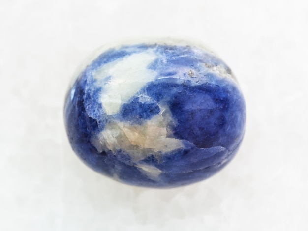 Tumbled Sodalite gem stone on white marble