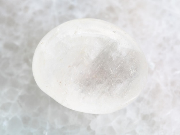 Tumbled white agate gemstone on white marble