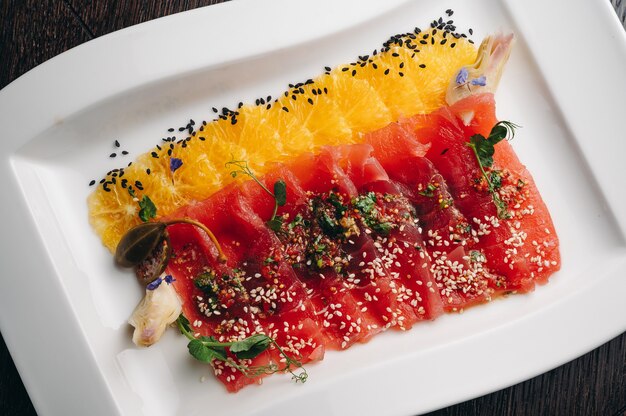 Photo tuna carpaccio with orange on a white plate