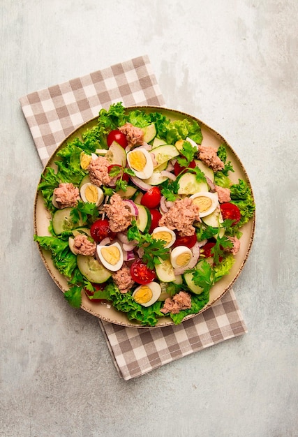 Tuna salad vegetable salad with quail eggs lettuce red onion and cucumbers on a light gray table keto food lifestyle healthy eating selective focus top view no people