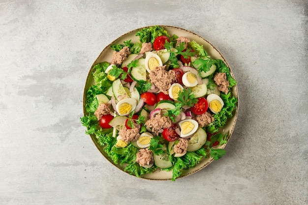 Tuna salad vegetable salad with quail eggs lettuce red onion and cucumbers on a light gray table keto food lifestyle healthy eating selective focus top view no people