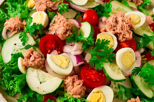 Tuna salad vegetable salad with quail eggs lettuce red onion and cucumbers on a light gray table keto food lifestyle healthy eating selective focus top view no people