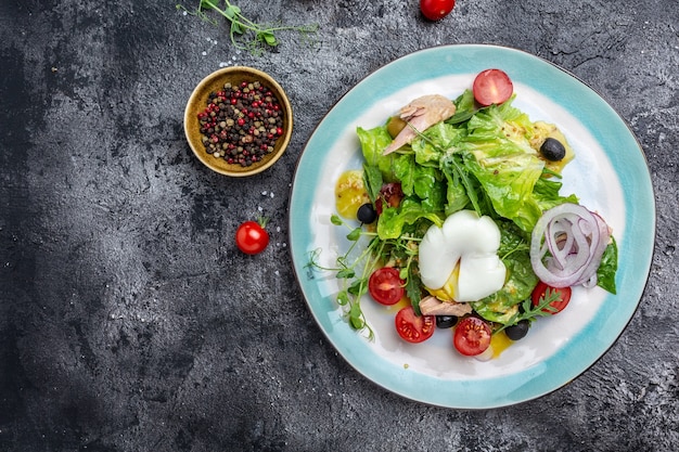 Tuna salad with poached, egg, lettuce, cherry, tomatoes olives and corn