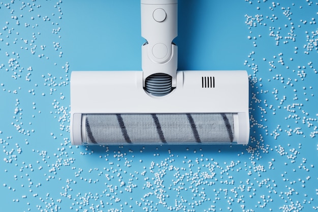 The turbo brush of the vacuum cleaner cleans white balls, top view on a blue background. The concept of cleanliness and cleaning.