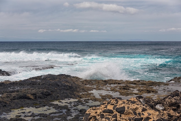 Turbulent ocean waves with white foam beat coastal stones