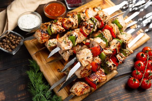 Turkey or chicken shish kebab on metal skewers with pepper tomatoes and onion on rustic wooden table