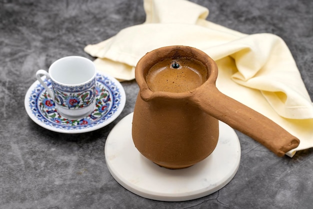 Turkish coffee in an earthen pot on a dark background Traditional Turkish cuisine flavor close up