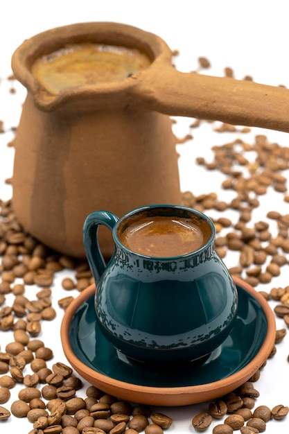 Turkish coffee on a white background Rustic cup and earthen coffee pot Scattered coffee beans on the ground