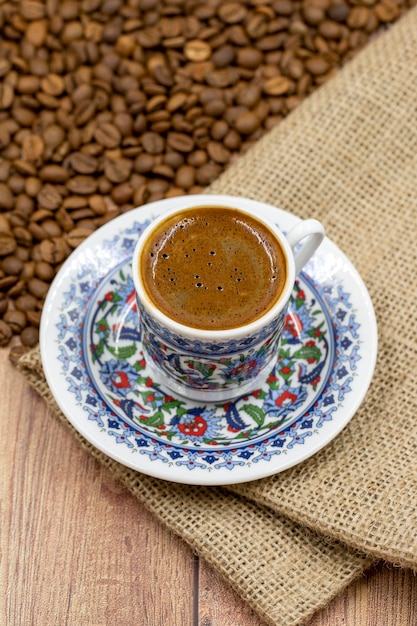 Turkish coffee on wood floor Classic Turkish coffee cup on cloth coffee beans in the background Close up