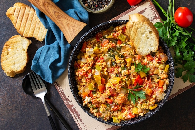 Turkish cuisine Menemen Scrambled eggs in a cast iron frying pan Top view flat lay background