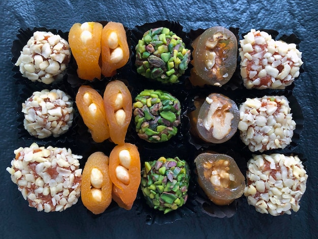 Turkish sweets, Turkish dried fruits with nuts, oriental sweets on black background, Asian cuisine