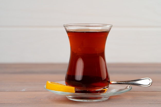 Turkish tea in glass cup with piece of lemon on wooden table close up