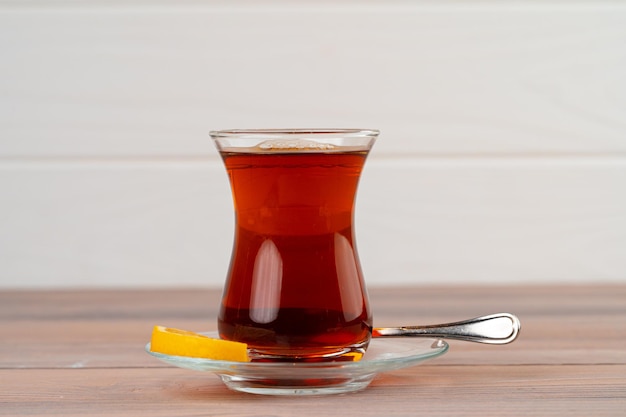 Turkish tea in glass cup with piece of lemon on wooden table