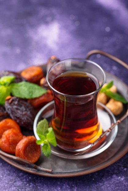 Turkish tea in traditional glass with dried fruits