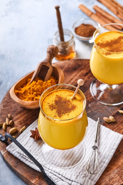 Turmeric golden milk latte with cinnamon sticks and honey. Healthy ayurvedic drink. Trendy Asian natural detox beverage with spices for vegans. Copy space.