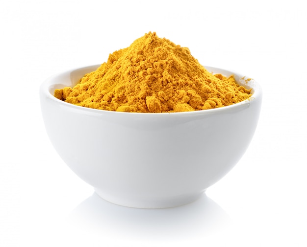 Photo turmeric powder in a bowl on white space