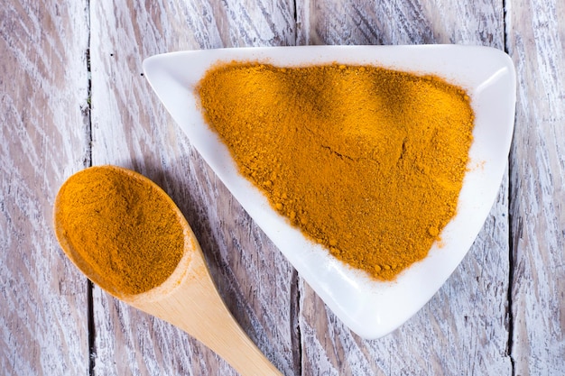 Turmeric powder in bowl on wooden table curcuma longa