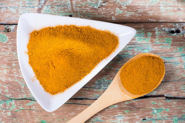 Turmeric powder in bowl on wooden table curcuma longa