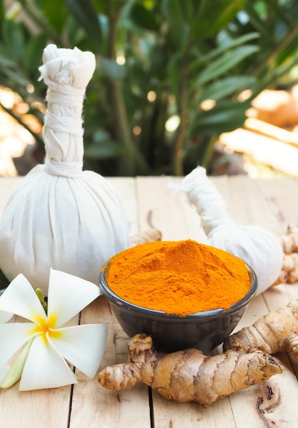 Turmeric powder and fresh turmeric (Curcuma) in black bowls on old wooden table