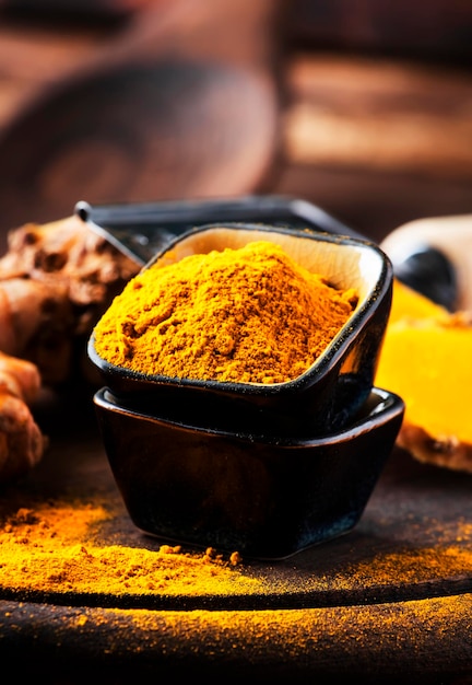 Turmeric powder and fresh turmeric on wooden background with copy space