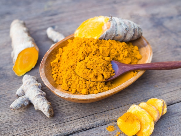 Turmeric powder and turmeric in wood bowl on wood table