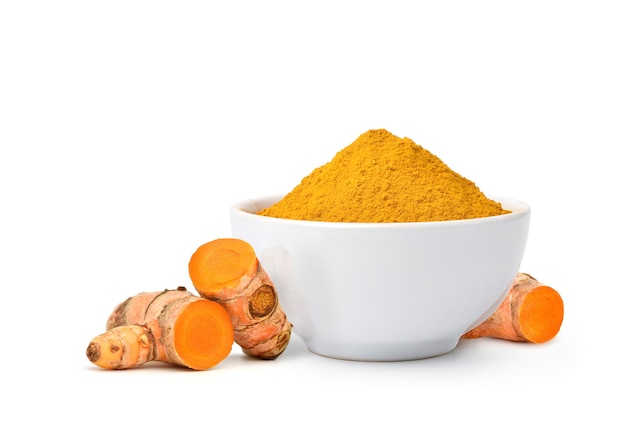 Turmeric powder in white bowl with  rhizome slices isolated on white