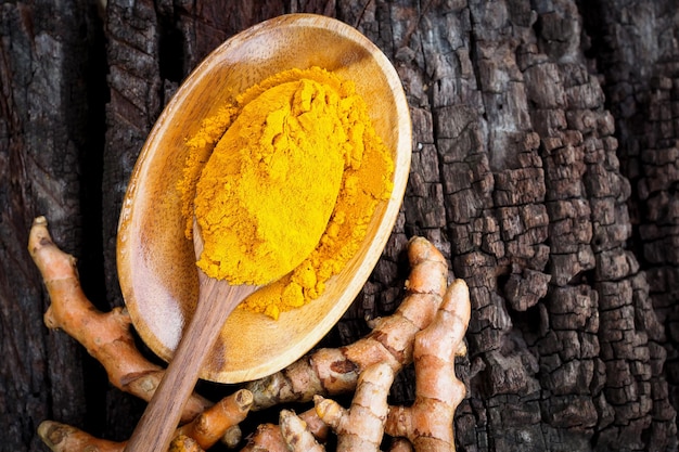 Turmeric powder in wooden spoon on old wooden table herbal