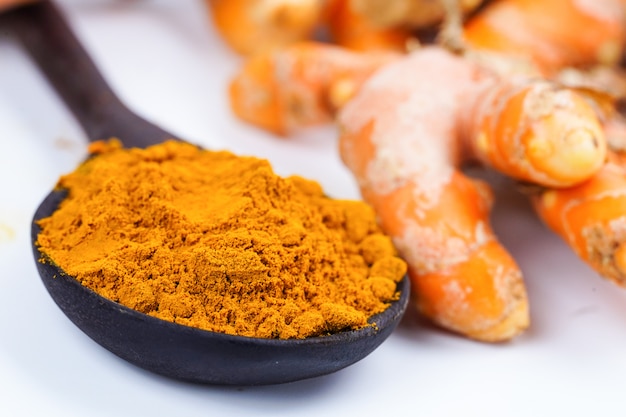 Turmeric roots and powder herb on wooden background.