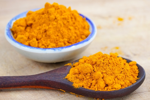 Turmeric roots and powder herb on woodensurface.