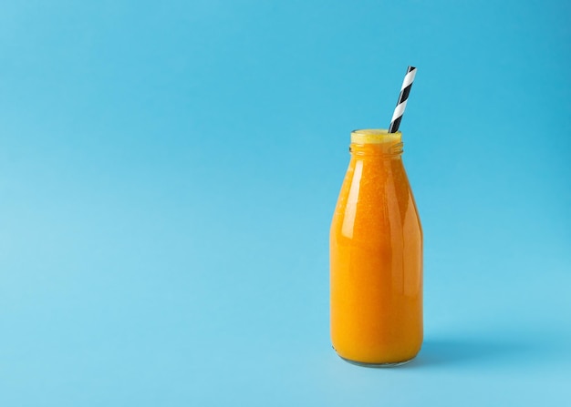 Turmeric smoothie in glass bottle with ingredients turmeric powder on blue background