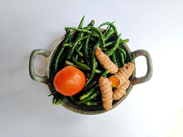 Turmeric tomato and green curly chilies on the mini pan isolated on white background seasoning