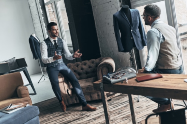 turning ideas into clothing. two young fashionable men having a discussion and smiling 