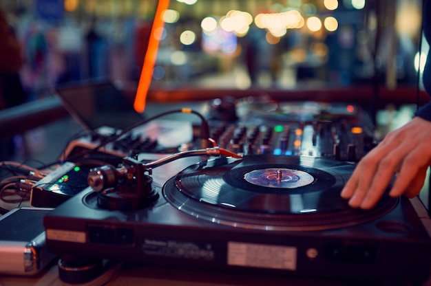 Turntable, hand of dj on the vinyl record at night club.