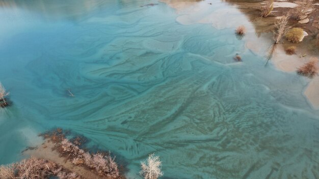 Turquoise-blue mirror water with trees in a mountain lake. Divorces from the current.