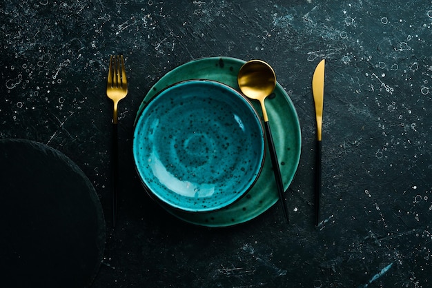 Turquoise plate and cutlery on a black stone background Top view Rustic style