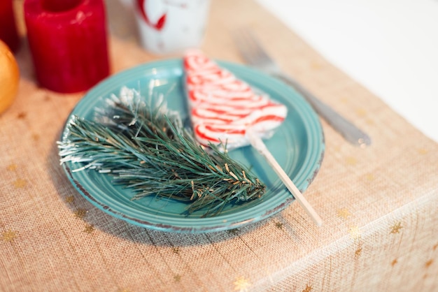 Turquoise Plate on Table with Christmas Tree Branch and Lollipop Christmas Concept