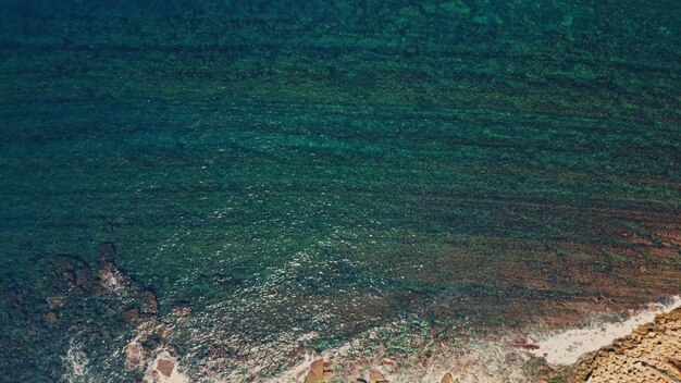 Turquoise sea waves rippling under summer sunlight aerial view clear blue ocean