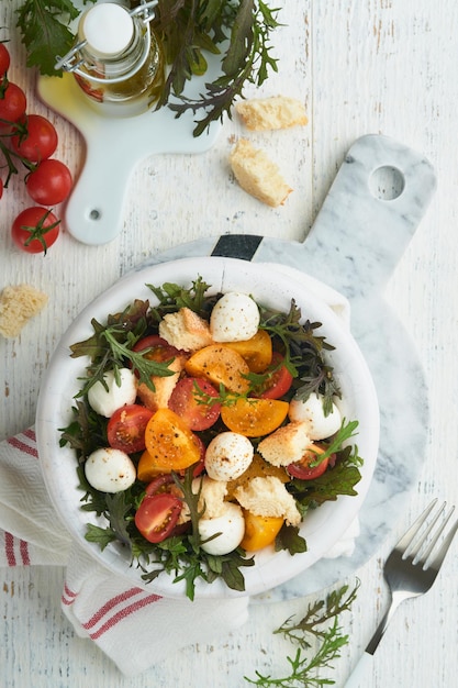 Tuscan Panzanella Cherry Tomatoes salad with arugula basil mozzarella and bread crackers on white bowl Traditional italian salad Mediterranean healthy food and cuisine