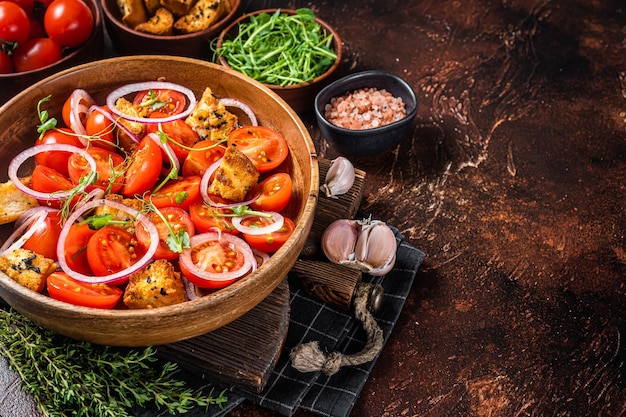 Tuscan Panzanella salad, Vegetarian classic salad with tomatoes, onion and Croutons. Dark background. Top view. Copy space.