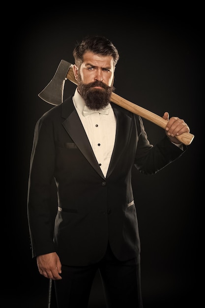 Tuxedo party boss brutal man hispter hold axe black background confident businessman formal suit serious male barber with ax Barbershop tuxedo man with beard mustache grooming with sharp blade