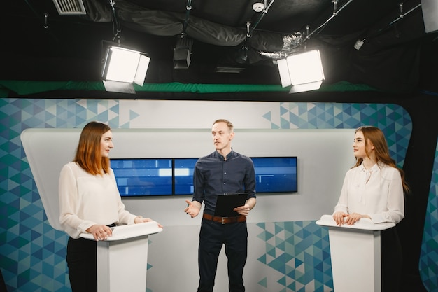 TV game show with two participants answering questions or solving puzzles and host. Smiling women participate in television quiz.