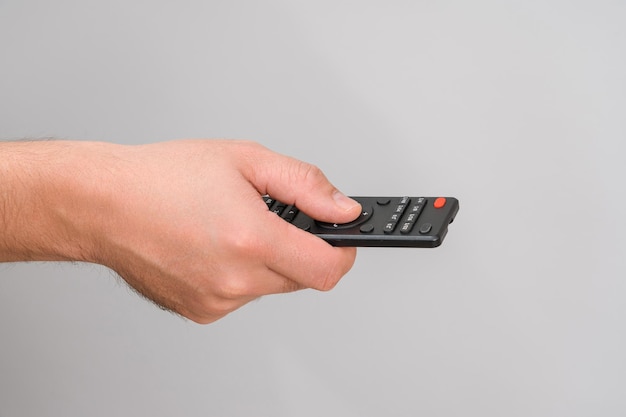 TV remote control in a man's hand on a gray background, close-up