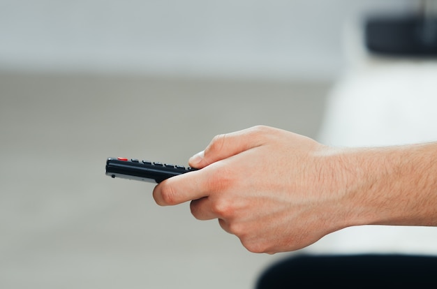 The TV remote in hand, in a cozy home atmosphere, in front of the TV