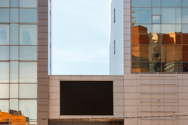 TV screen on business building. Large blank black screen of TV layout Billboard. Template for placing ads on wall of modern building. Empty large Billboard black led screen on building