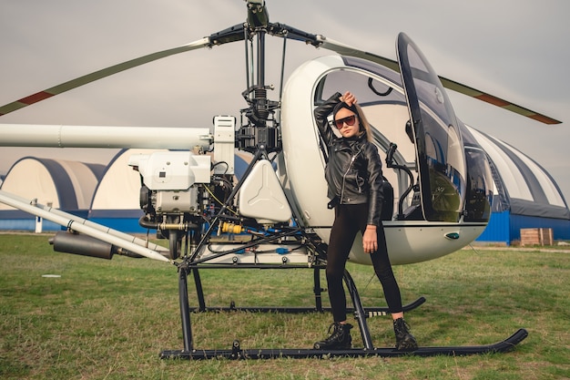 Tween girl in black clothes standing near helicopter