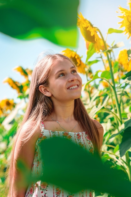 A twelve-year-old teenage girl walks in a field of sunflowers