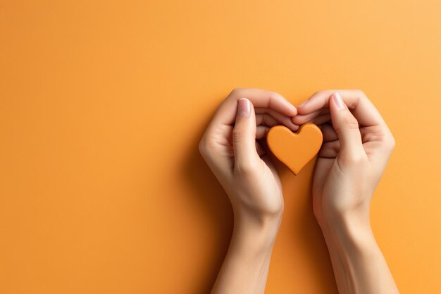 Twi hands holding a heart over a lay flat background